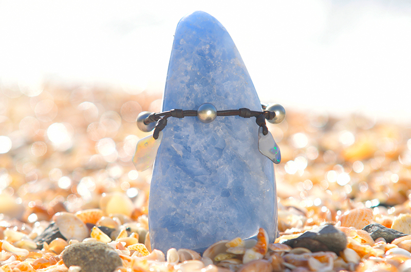 Bracelet or anklet with opals and Tahitian pearls displayed around a blue stone on seashells