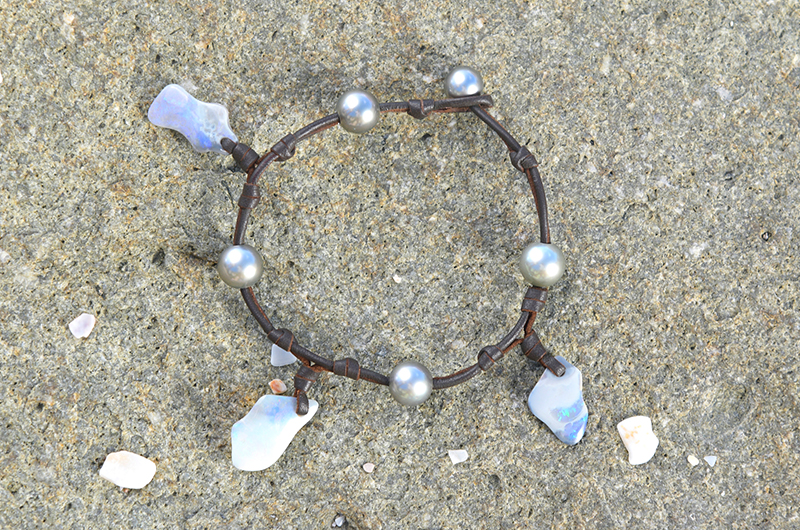 Full view of the bracelet or anklet with opals and Tahitian pearls displayed on the sand