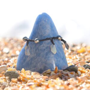 Bracelet ou chevillère en cuir avec opales et perles de culture de Tahiti présenté autour d’une pierre bleue sur la plage
