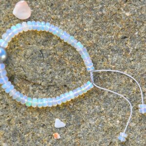 Vue d’ensemble du bracelet ajustable avec opales et une perle de Tahiti ronde présenté sur le sable