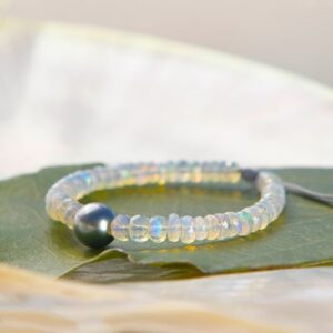 Bracelet ajustable avec opales et une perle de culture de Tahiti ronde présenté sur une feuille verte