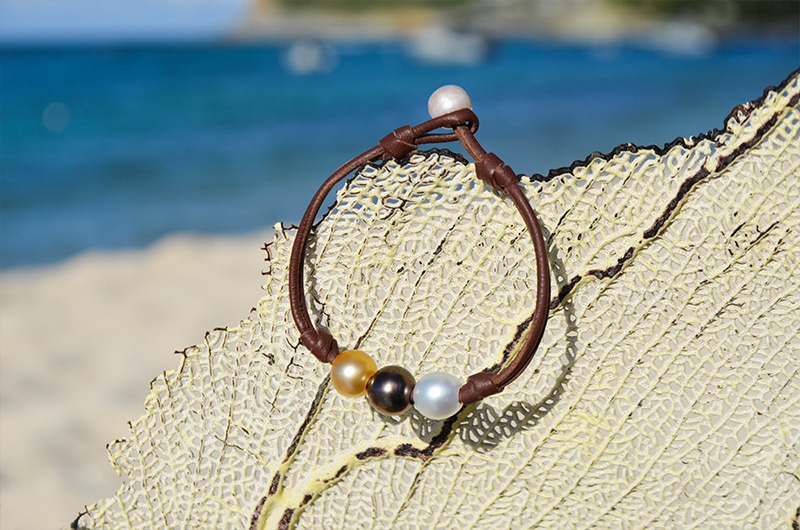 Full view of the bracelet with three multicolored pearls displayed on a sea fan
