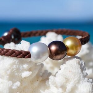 Bracelet tressé avec trois perles multicolores présenté sur du corail face à la mer