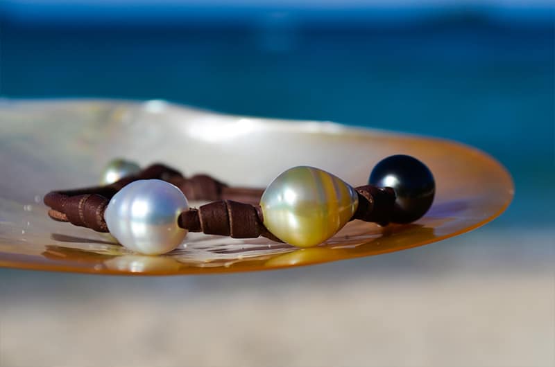Bracelet with three multicolored circled pearls and knots displayed on mother-of-pearl