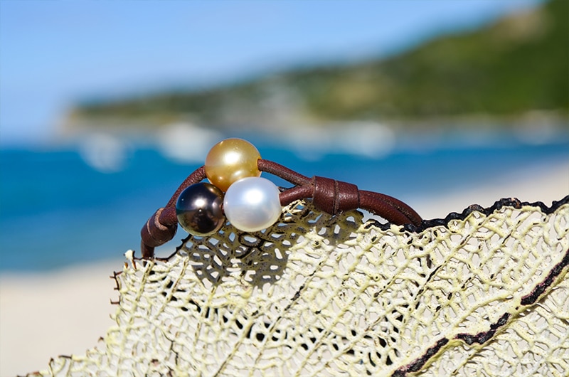 Two-row bracelet with three multicolored pearls displayed on a sea fan