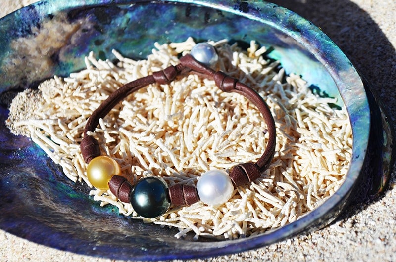 Full view of the bracelet with three multicolored pearls displayed in mother-of-pearl on coral