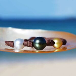 Bracelet en cuir marron avec trois perles de culture multicolores et nœuds présenté sur une nacre