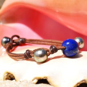 Bracelet avec perles de Tahiti et lapis-lazuli présenté sur un coquillage avec un fond rose
