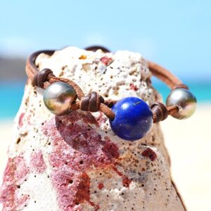 Bracelet en cuir marron avec perles de culture de Tahiti et lapis-lazuli présenté autour d’une roche claire