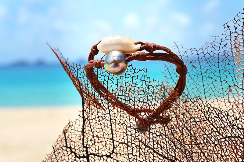 Vue d’ensemble du bracelet avec une perle de Tahiti et un coquillage présenté sur un éventail de mer