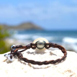Vue d’ensemble du bracelet tressé avec anneau de nacre, perle de Tahiti et Keshi présenté sur une roche