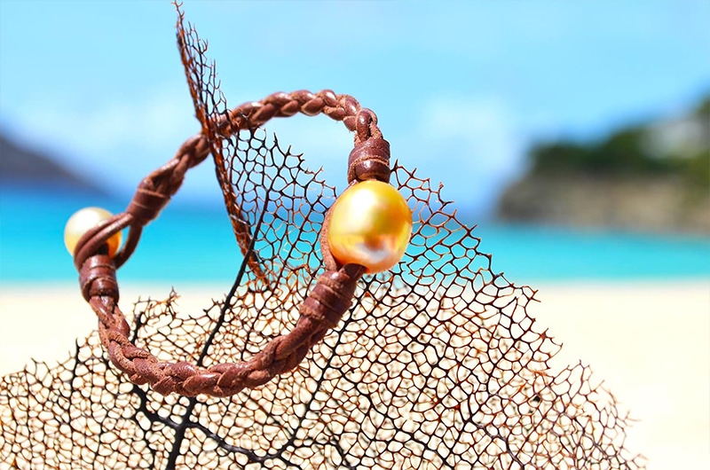 Vue d’ensemble du bracelet tressé avec une perle d’Australie présenté sur un éventail de mer