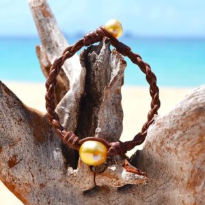 Brown braided leather bracelet with an Australian cultured pearl displayed on wood by the sea