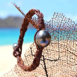 Bracelet large en cuir marron tressé avec une perle de culture de Tahiti présenté sur un éventail de mer