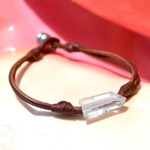 Bracelet en cuir marron avec une perle de culture de Tahiti et un cristal de roche présenté sur un fond rose