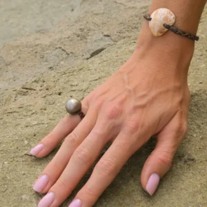 Autre vue du bracelet avec coquillage blanc et perle de Tahiti porté au poignet sur une roche