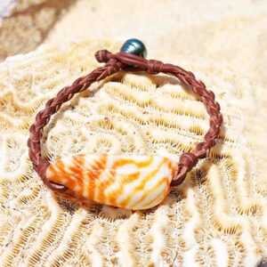 Vue d’ensemble du bracelet avec coquillage orange et perle de Tahiti présenté sur du corail