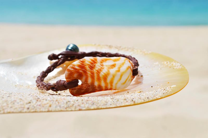 Bracelet with an orange shell and Tahitian pearl displayed on mother-of-pearl