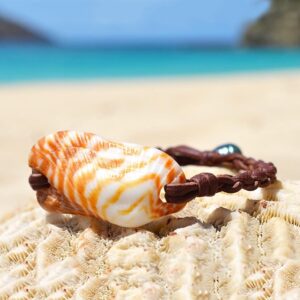 Bracelet en cuir marron avec un coquillage orange et une perle de culture de Tahiti présenté sur du corail face à la mer