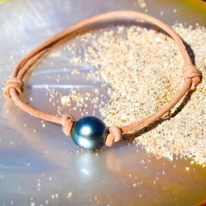 Adjustable leather bracelet with a 10.5 mm semi-round Tahitian pearl displayed on mother-of-pearl and sand