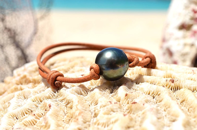 Adjustable leather bracelet with a 13.5 mm Tahitian pearl displayed on coral