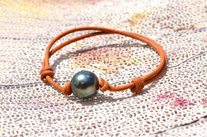 Adjustable leather bracelet with a 13.5 mm Tahitian pearl displayed on a decorative net