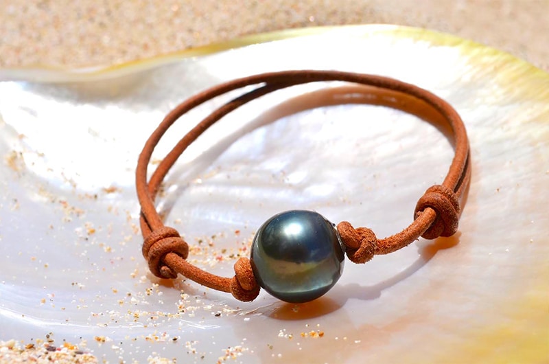 Full view of the adjustable bracelet with a 13.5 mm Tahitian pearl displayed on mother-of-pearl