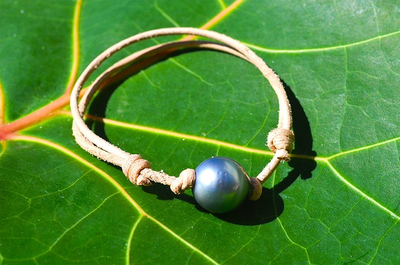 Vue d’ensemble du bracelet ajustable avec une perle de Tahiti cerclée de 13 mm présenté sur une feuille verte