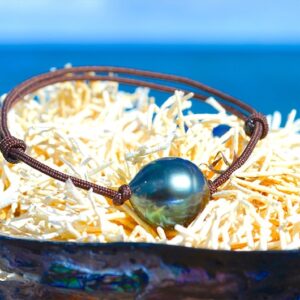 Adjustable bracelet with a 13 mm circled Tahitian pearl displayed on a shell by the sea
