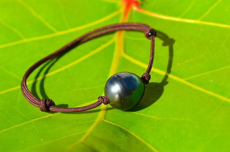 Full view of the adjustable bracelet with a 13 mm circled Tahitian pearl displayed on a green leaf