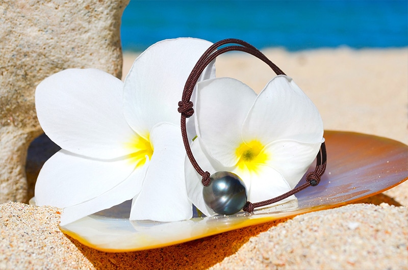 Adjustable bracelet with a 13 mm circled Tahitian pearl displayed on mother-of-pearl with white flowers
