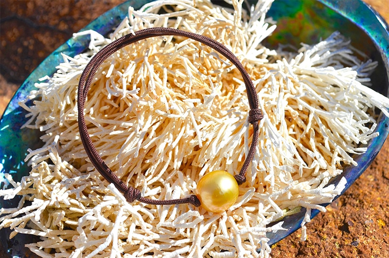 Bracelet ajustable avec une perle dorée d’Australie de 11,5 mm présenté sur un coquillage
