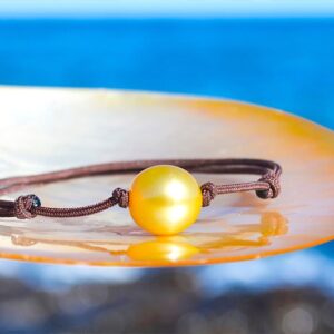 Bracelet ajustable avec une perle dorée d’Australie de 11,5 mm présenté sur une nacre face à la mer