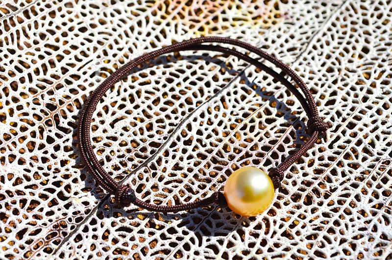 Bracelet ajustable avec une perle dorée d’Australie de 9 mm présenté sur du corail blanc