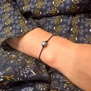 Adjustable MOKUBA cord bracelet with a 9.5 mm semi-round Tahitian pearl worn on the wrist in close-up