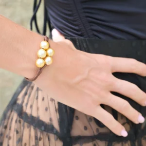 Bracelet en cuir avec cinq perles dorées d’Australie porté au poignet en vue rapprochée