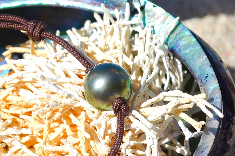Detail of the 10.5 mm semi-round Tahitian pearl on the adjustable bracelet displayed on a shell