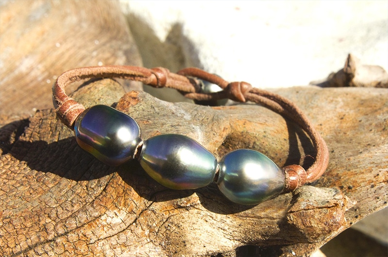 Vue d’ensemble du bracelet en cuir avec trois perles semi-baroques de Tahiti présenté sur du bois