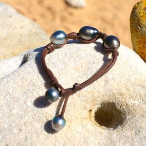 Bracelet with three 11.5 mm Tahitian pearls, knots and two closure pearls displayed on a rock