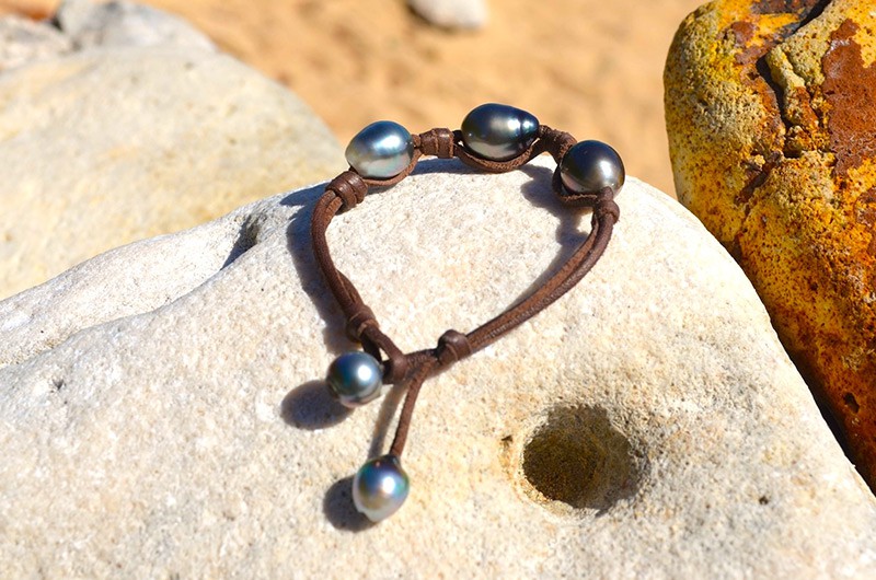 Bracelet with three 11.5 mm Tahitian pearls, knots and two closure pearls displayed on a rock
