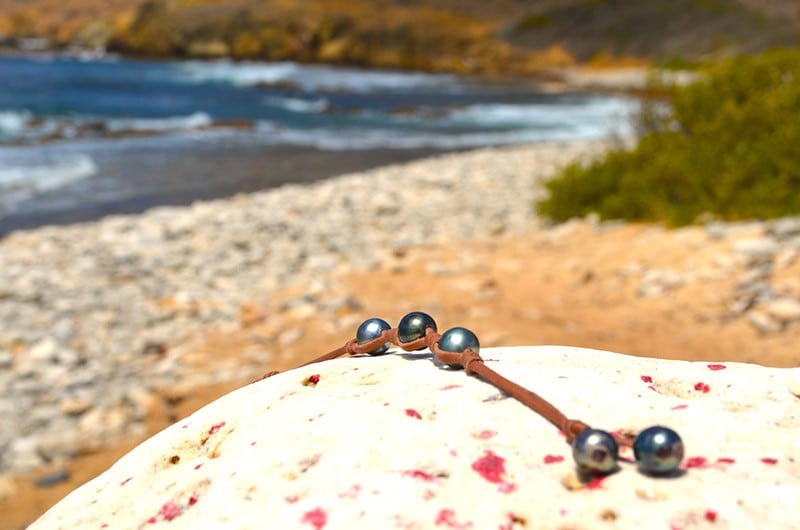 Bracelet with three 9.5 mm Tahitian pearls, knots and two closure pearls displayed on a rock by the sea