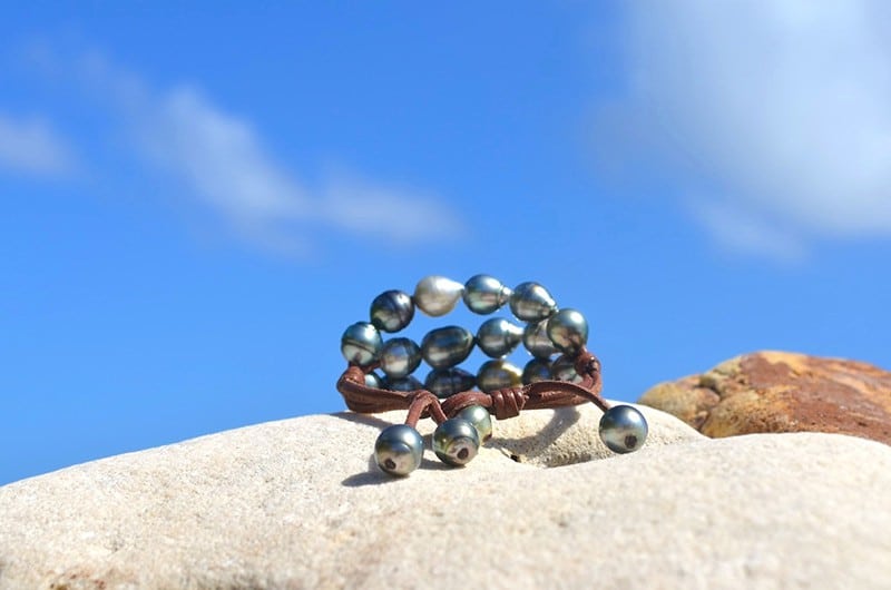 Détail des vingt perles baroques de Tahiti et du montage à trois rangs du bracelet présenté sur une roche