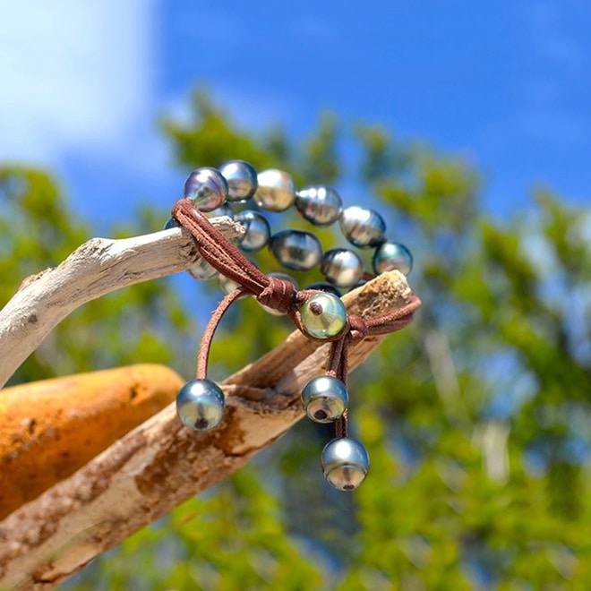 Bracelet en cuir marron à trois rangs avec vingt perles baroques de Tahiti présenté en vue complète sur fond de ciel bleu