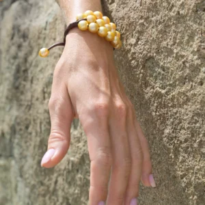 Three-strand bracelet with twenty golden Australian pearls worn on the wrist in close-up