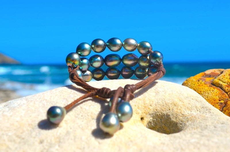 Bracelet à trois rangs avec vingt perles semi-baroques de Tahiti présenté sur du corail face à la mer