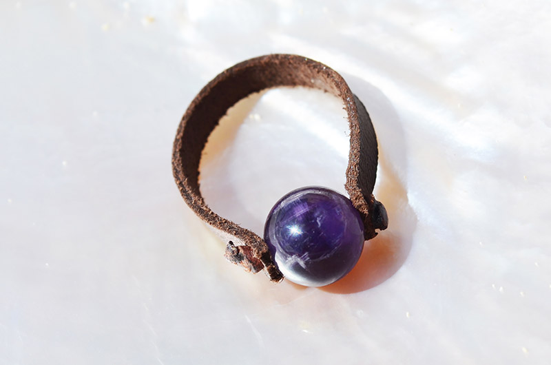 Bague en cuir marron avec améthyste ronde de 10 mm présentée sur une nacre