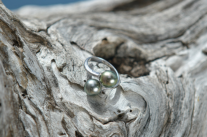 Sterling silver Toi et Moi ring with two Tahitian pearls displayed on driftwood