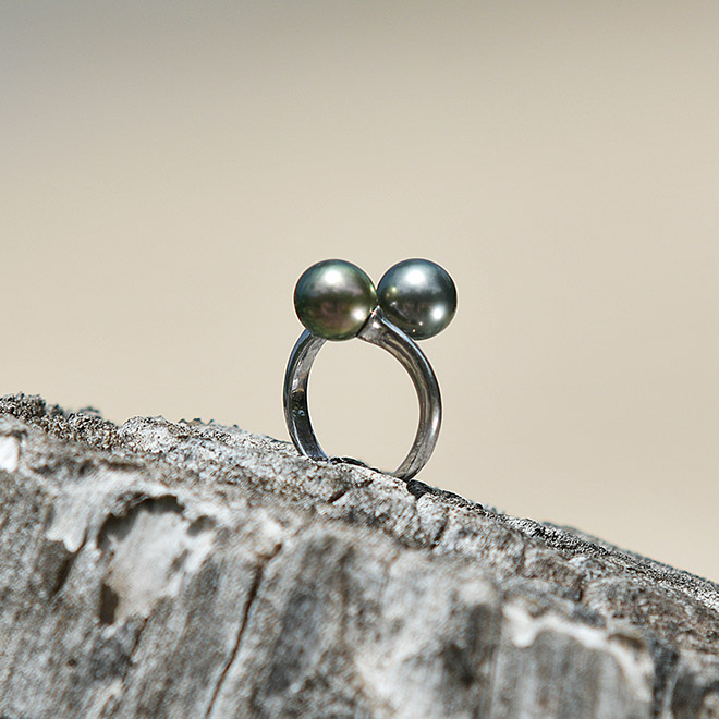 Sterling silver Toi et Moi ring with two Tahitian cultured pearls displayed on a natural surface