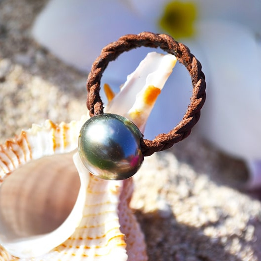 Braided brown leather ring with one Tahitian cultured pearl, displayed on a seashell