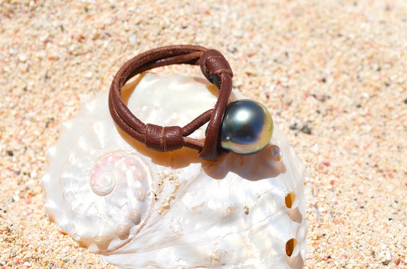 Leather ring with a 10 mm Tahitian pearl displayed on a shell and sand